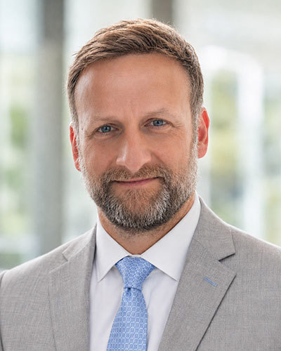 Elliot Servais, MD, in a gray suit and blue tie